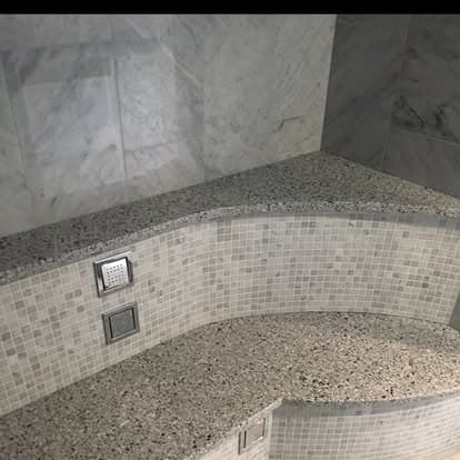 Luxury shower with curved mosaic tile bench and granite cap